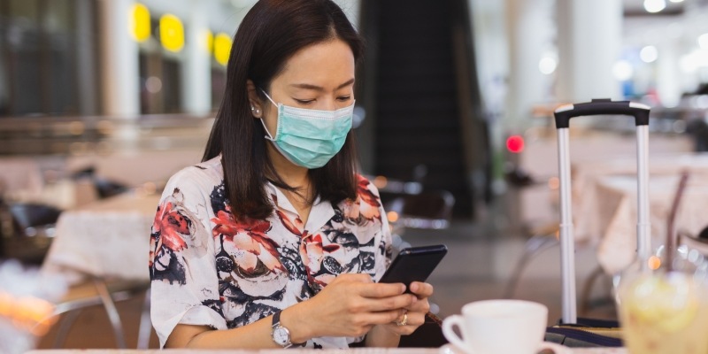 Reisende am Flughafen mit Corona Mundschutz Maske